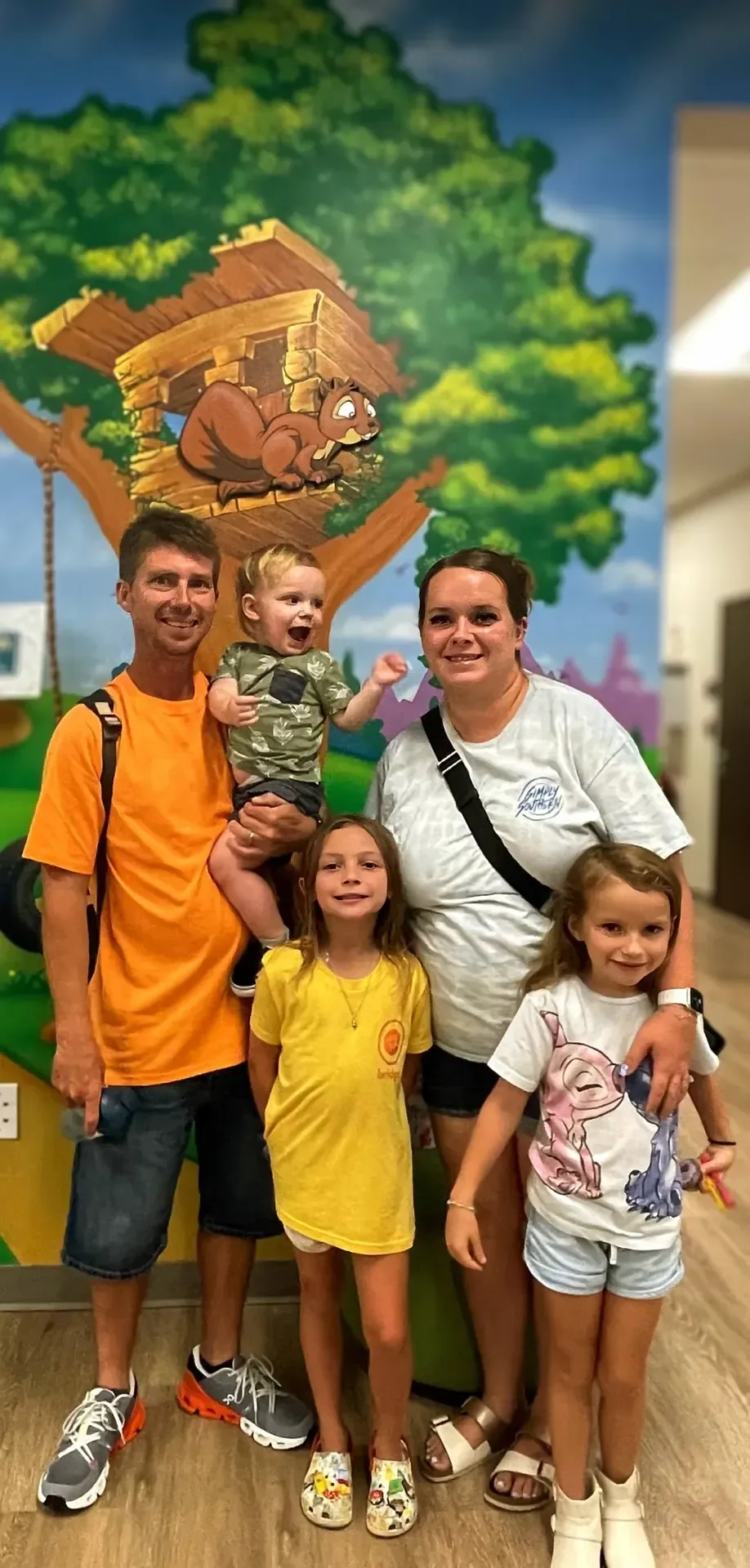 A man, a woman and three young children smiling together in a colorful play area