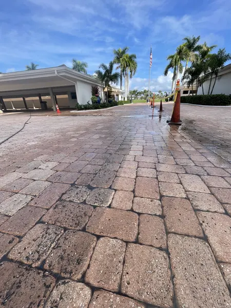 Clean brick paver driveway leading to a low commercial building with an orange cone at the edge