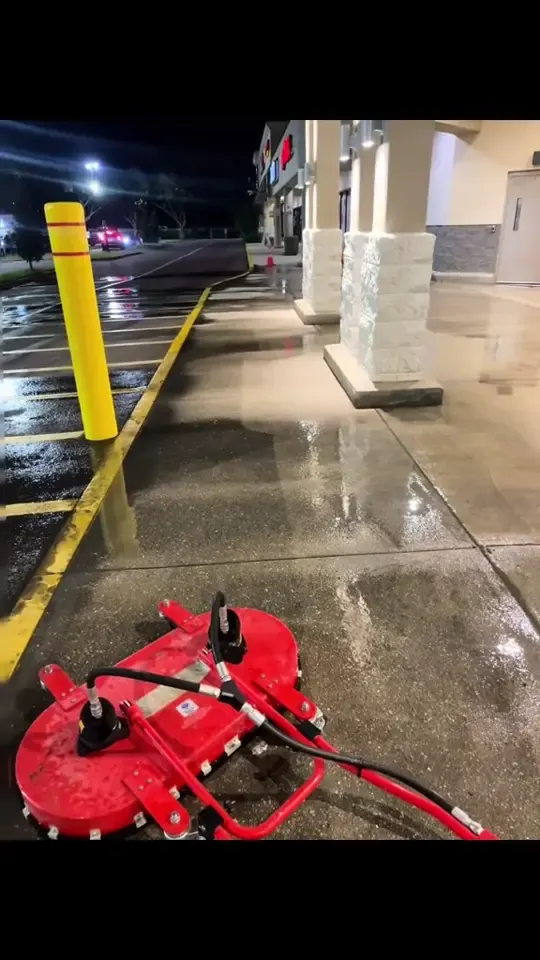 A red surface cleaner on a wet concrete sidewalk at night, then the washed lot.