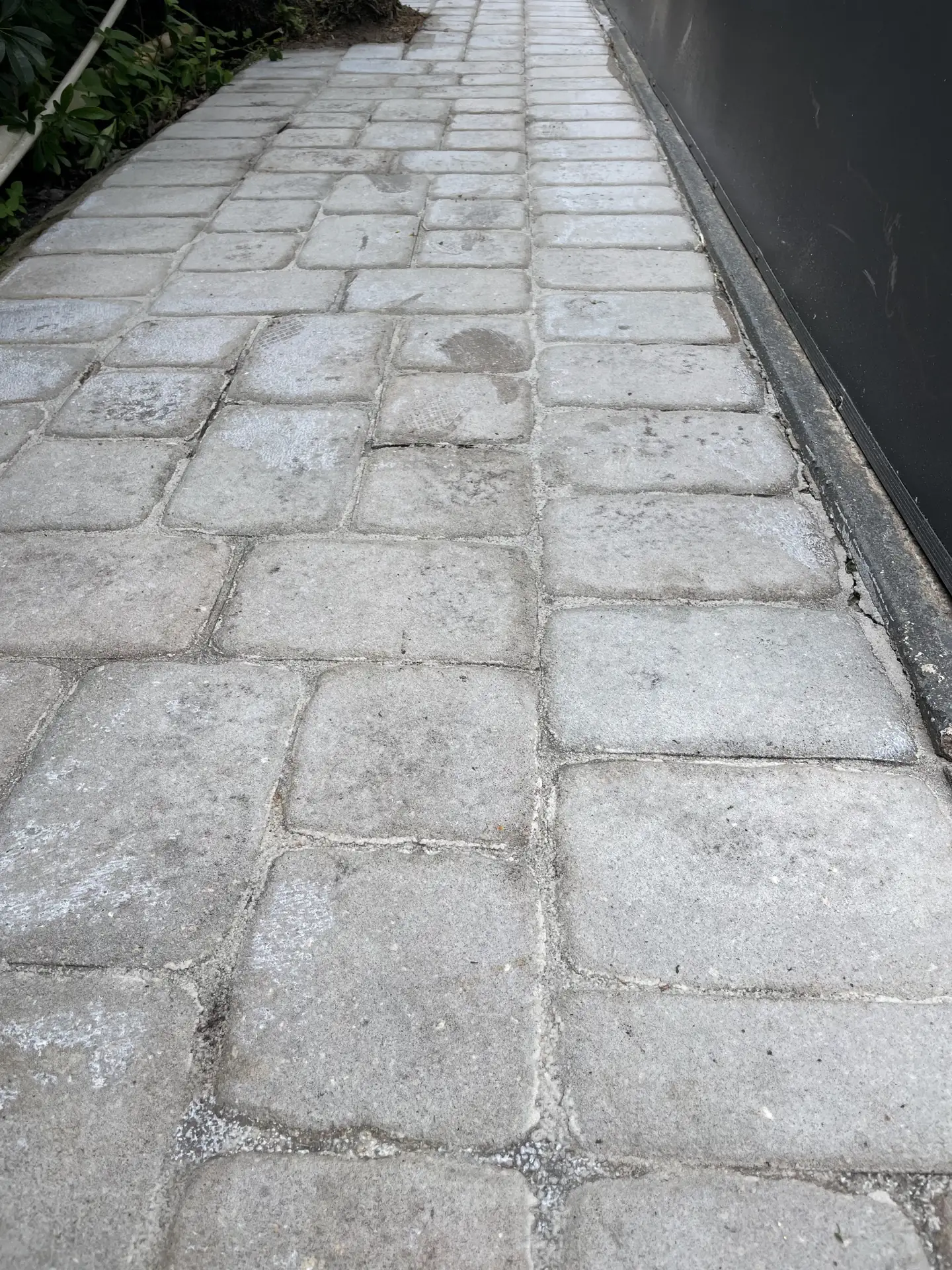 Gray, chalky pavers along a walkway beside a dark wall