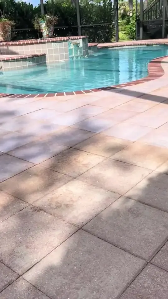 Weathered pool deck slabs and pavers cleaned with a rotary surface cleaner inside screen enclosures.