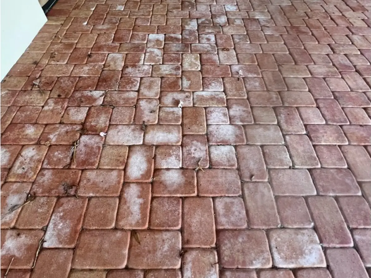 Red pavers with white haze and streaks on a covered patio